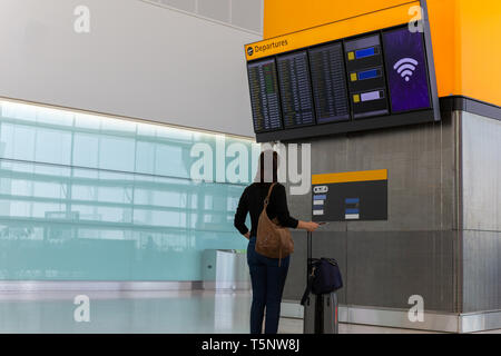 Femme avec un bagage à main à la recherche de l'information de vol dans l'aéroport. Banque D'Images