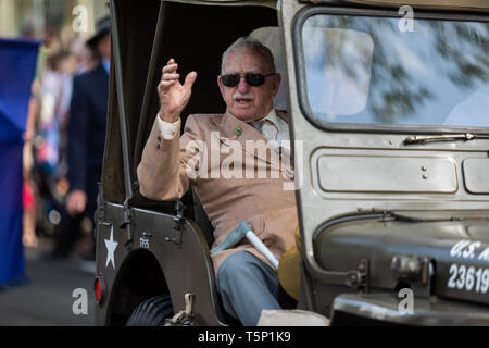 Un vieux vétéran retourné dans son véhicule, gesticulant, giving Thumbs up à la foule acclamant et applaudissant pour lui, lors de l'Anzac Day march Banque D'Images