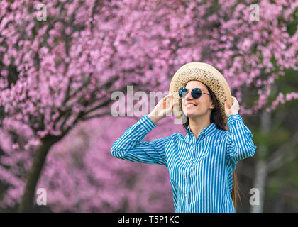 Belle jeune femme dans les fleurs de cerisier en fleurs jardin Banque D'Images