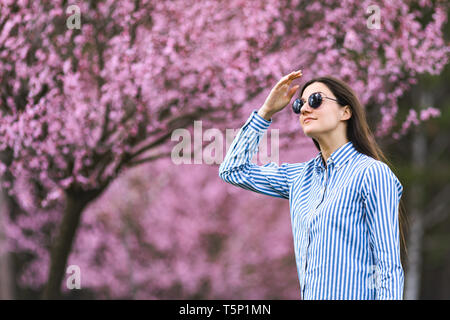 Belle jeune femme dans les fleurs de cerisier en fleurs jardin Banque D'Images