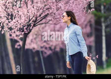 Belle jeune femme dans les fleurs de cerisier en fleurs jardin Banque D'Images