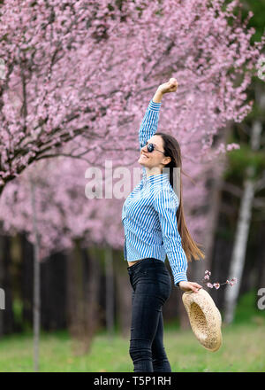 Belle jeune femme dans les fleurs de cerisier en fleurs jardin Banque D'Images