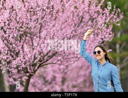 Belle jeune femme dans les fleurs de cerisier en fleurs jardin Banque D'Images