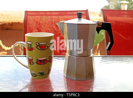 Moka pot avec une tasse de café sur la table avec chaise rouge dans la toile Banque D'Images