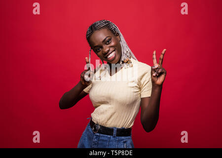 Portrait d'une femme africaine montrant la victoire avec les doigts sur fond rouge Banque D'Images
