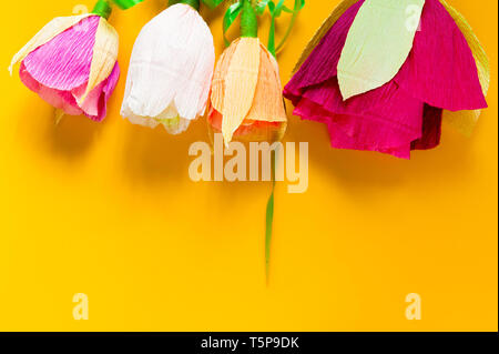 Des fleurs en papier ondulé sur fond jaune Banque D'Images