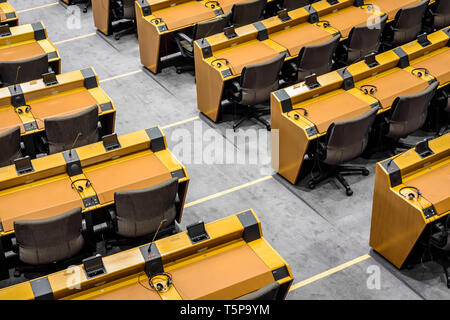 Vue rapprochée d'un bureau vide avec microphones, casques et matériel de vote électronique dans l'hémicycle du Parlement européen à Bruxelles. Banque D'Images