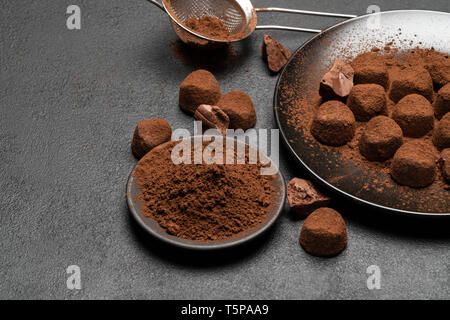 Truffes au chocolat bonbons et poudre de cacao foncé sur fond de béton Banque D'Images