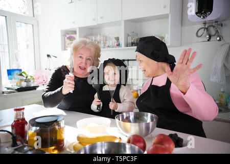 Family eating pancakes et boire le thé dans la cuisine. Posant pour l'appareil photo Banque D'Images