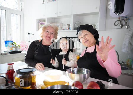 Family eating pancakes et boire le thé dans la cuisine. Posant pour l'appareil photo et des signes avec la main Banque D'Images