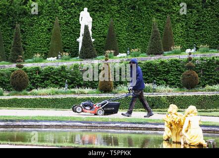 Paris, Paris. Apr 25, 2019. Un homme tond la pelouse au Palais de Versailles, à l'ouest de Paris, le 25 avril 2019. Le Palais de Versailles, l'un des sites historiques les plus populaires pour les touristes en France, est célèbre pour ses capacités et la conception des jardins, ainsi que la représentation de la culture française et de l'histoire royale. Credit : Gao Jing/Xinhua/Alamy Live News Banque D'Images