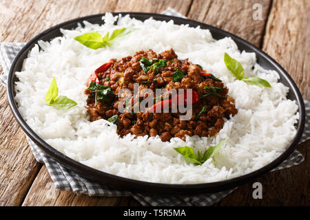Recette de poulet au basilic thaï avec piment et sauce soja avec du riz garnir close-up sur une plaque sur la table horizontale. Banque D'Images