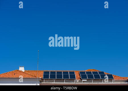 Deux rangées de moderne, propre des panneaux solaires sur le toit de tuiles rouges chambre avec ciel bleu clair à été ensoleillé jour with copy space Banque D'Images