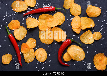 Croustilles de pommes de terre avec saveur piment et le sel sur la surface de la table en pierre sombre mise à plat vue supérieure Banque D'Images