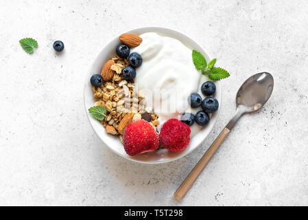 Barres granola avec yogourt et petits fruits pour déjeuner sain. Bol de granola avec yogourt grec, les amandes, les bleuets et les fraises, vue du dessus, copiez l'espace. Banque D'Images