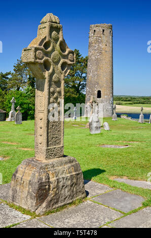 L'Irlande, dans le comté d'Offaly, le monastère de Clonmacnoise, Règlement réplique de la Croix du Sud avec tour ronde à l'arrière-plan. Banque D'Images