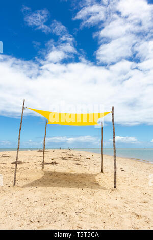 Belle vue sur la plage avec une tente jaune aux beaux jours d'été et la mer et ciel bleu en arrière-plan. Concept de vacances, calme et repos. Bahia. Banque D'Images