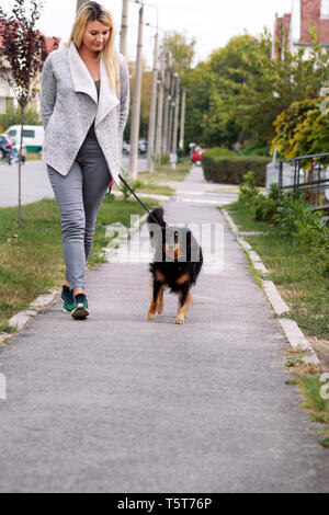 Femme marche avec sa petite femelle race croisée chien en laisse, posant devant la caméra. Portrait de Dame, propriétaire et mignon half breed dog jouit. Banque D'Images