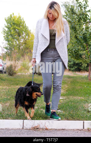 Femme marche avec sa petite femelle race croisée chien en laisse, posant devant la caméra. Portrait de Dame, propriétaire et mignon half breed dog jouit. Banque D'Images