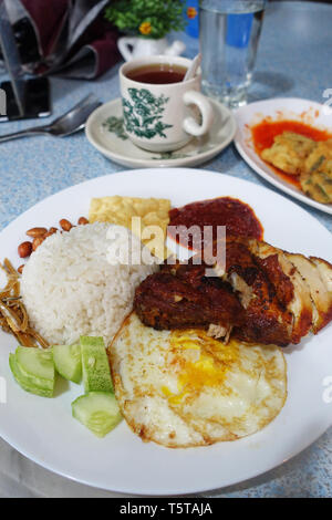 Nasi lemak, servi avec du riz à la noix de coco de Malaisie d'oeufs frits, de concombre, de l'anchois frits, d'arachides et de poulet en sauce chili Banque D'Images