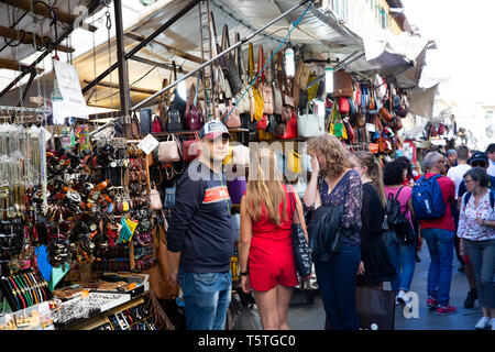 Blocage mâle propriétaire, est à l'appareil photo dans le marché San Lorenzo à Florence, avec des dames de boutiques à proximité,Toscane,Italie Banque D'Images