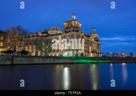 Bâtiment du parlement allemand Reichstag illuminée et son dôme en verre par la rivière Spree à Berlin, en Allemagne, au crépuscule. Banque D'Images