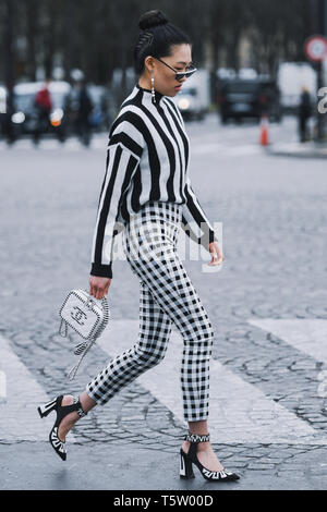 Paris, France - le 5 mars 2019 : Street style - femme vêtu de noir à rayures blanches, pantalon à carreaux et cavalier sac Chanel, avant qu'un pari fashion show Banque D'Images