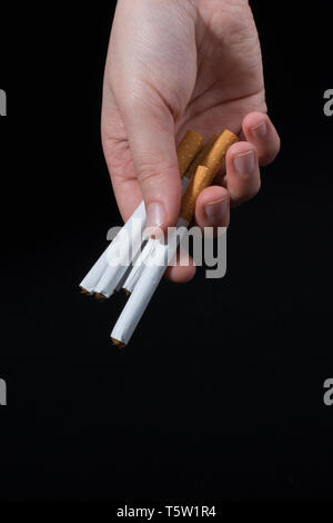 La main est de donner des paquet de cigarettes sur fond noir Banque D'Images