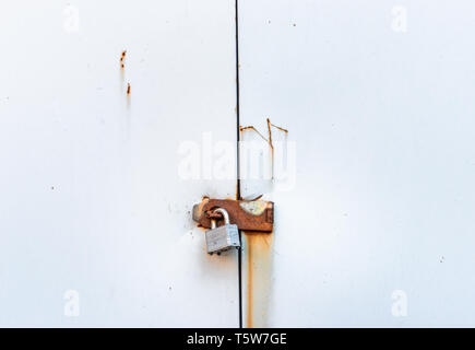 Simple cadenas verrouillé métal rouillé accroché sur le métal ordinaire sur hasp portes de l'abri de jardin. Banque D'Images