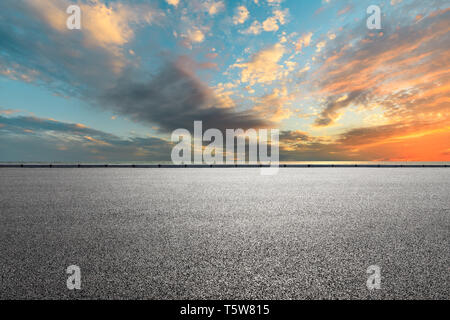 Route asphaltée vide et la mer avec de beaux nuages au coucher du soleil Banque D'Images