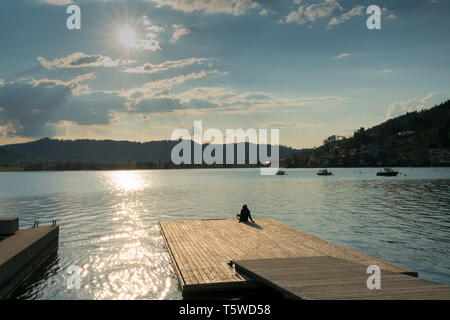 Silhouette d'une femme de détente sur un quai flottant sur le lac Aegerisee en Suisse au coucher du soleil Banque D'Images