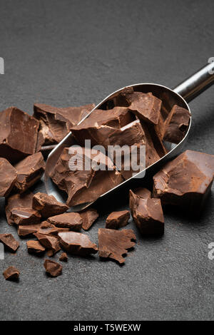 Morceaux de chocolat noir en metal scoop sur fond de béton foncé Banque D'Images