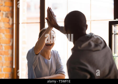 Guy africains et caucasian girl offrant un rapport cinq rencontrez au café Banque D'Images