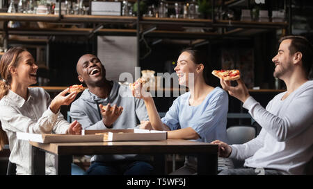 Société multiraciale friends laughing eating pizza réunis dans une pizzeria Banque D'Images