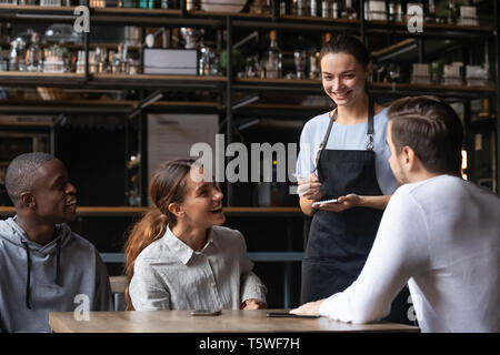 Divers friends sitting in restaurant passer commande parler avec serveuse Banque D'Images