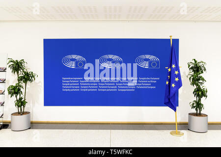 Vue de face d'un grand panneau bleu avec le logo et le nom du Parlement européen sur le mur avec un drapeau de l'Union européenne. Banque D'Images