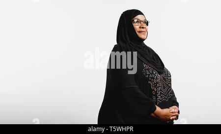 Les femme en hijab isolé sur fond blanc. Smiling woman arabe dans les lunettes et d'un hijab noir à la voiture. Banque D'Images