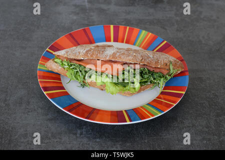 Sandwich baguette saumon fumé avec fusée roquette salade verte. Banque D'Images