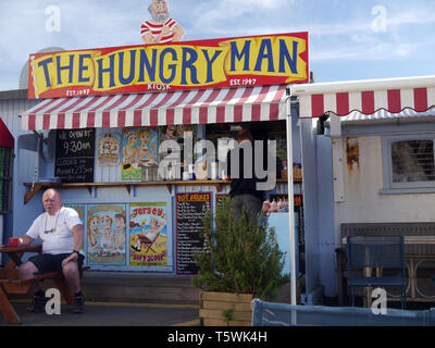 Deux hommes à l'extérieur de l'homme affamé café kiosque sur le quai dans Rozel Bay Harbour sur l'île de Jersey, Îles britanniques, Royaume-Uni. Banque D'Images