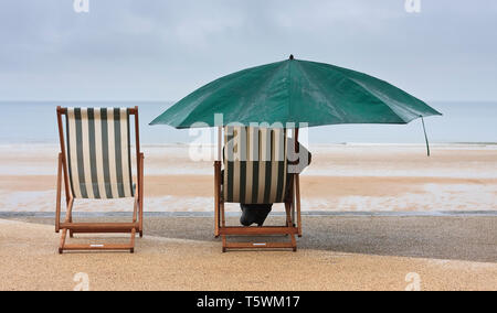 Pas de lever ce matin à Blyth cabines de plage, le littoral était entouré de brouillard et de la pluie, cela n'a pas empêché les habitants avec leurs chaises longues et parasol Banque D'Images