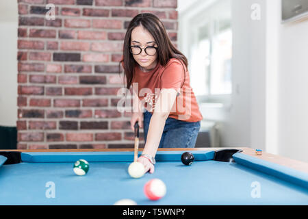 Urbain à la mode femme jouant au billard table de jeu de billard. Banque D'Images