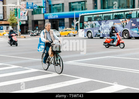 Taipei, Taiwan - le 26 avril 2019 : Taiwanese woman riding a bike de l'autre côté de la rue à l'intersection au cours d'une heure de pointe dans la ville de Taipei Banque D'Images