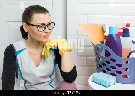 Femme adulte faisant le nettoyage avec des détergents. Femme dans les verres, uniformité professionnelle dans la salle de bain, wc. Banque D'Images