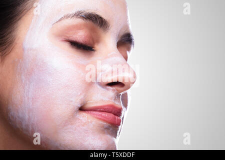 Belle jeune femme d'appliquer un masque facial Banque D'Images