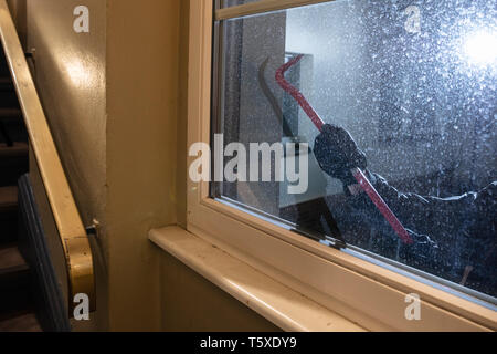 Cambrioleur essayant d'ouvrir la fenêtre avec pince de nuit Banque D'Images