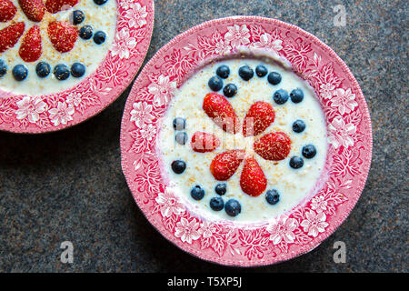 Céréales pour le petit déjeuner anglais. Plats traditionnels anglais anciens en céramique de porridge aux flocons d'avoine, décorés de fruits frais, de fraises et de bleuets. Banque D'Images