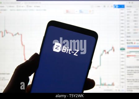 Montréal, Canada - le 26 avril 2019 : Le BIT-Z cryptocurrency logo change et l'application sur Android Samsung Galaxy S9 Plus dans la main sur un ordinateur portable Banque D'Images