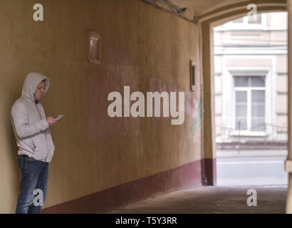 L'homme à la capuche avec le téléphone debout dans la cour de l'arche Banque D'Images