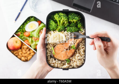 Male hands holding boîte à lunch à emporter avec des aliments sains. Pause déjeuner au bureau. Banque D'Images