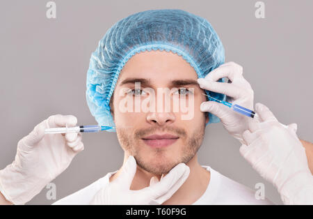 Visage de l'homme et de l'esthéticienne les mains avec des seringues injections de beauté Banque D'Images